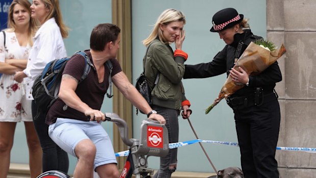 A woman wipes her eye as she speaks to a female police officer near to the scene of last night's terror attack.