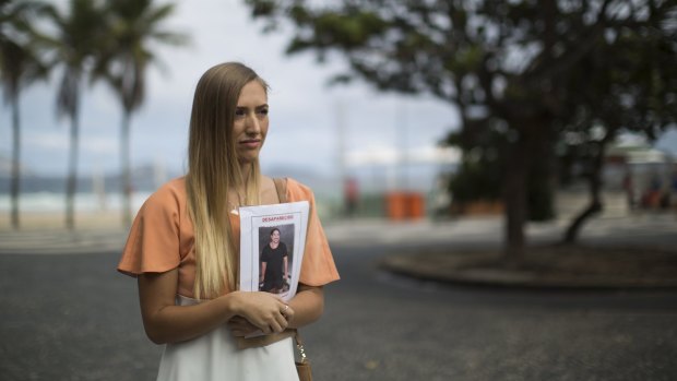 Bonnie Cuthbert holds a photo of Rye Hunt during the search in Rio de Janeiro. 