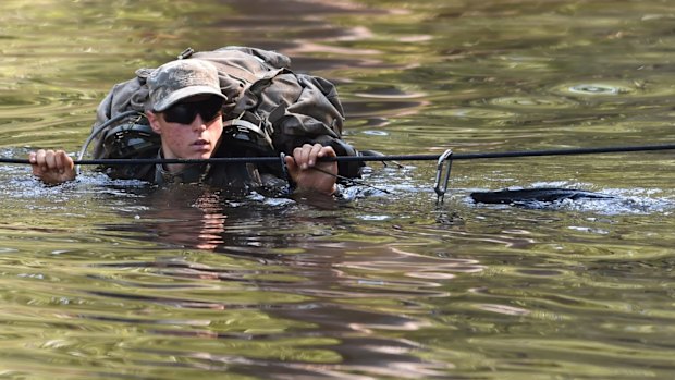 A female Army Ranger crosses the Yellow River on a rope bridge during Ranger School at Camp Rudder on Eglin Air Force Base, in Florida.