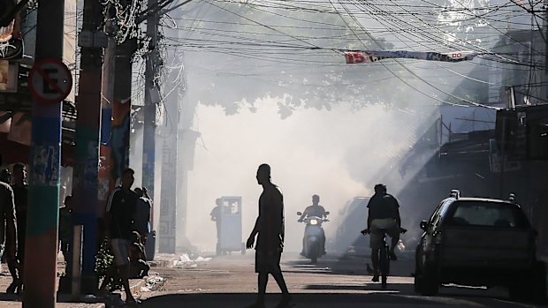 Garbage fire smoke lingers during an ongoing police operation.