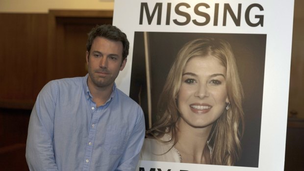 Ben Affleck in <i>Gone Girl</i>, with a poster of his missing wife. 