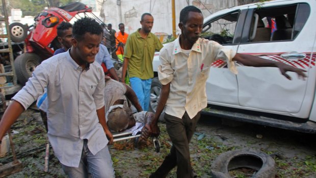 Somalis carry away the wounded civilian who was injured in a car bomb that was detonated in Mogadishu, on Saturday.