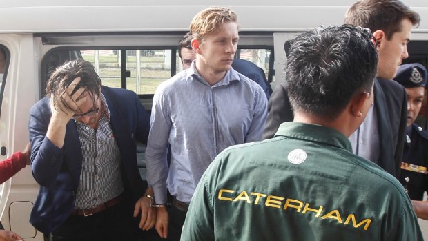 Nick Kelly, second left, and Thomas Whitworth, centre, two of the nine Australian men arrested arrive at the Sepang Magistrate in Sepang on Thursday.