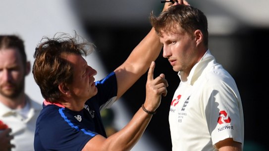 Joe Root is checked out by medical staff after being hit in the head.