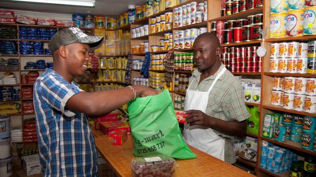 A customer packs his foodstuff in a cloth carrier bag in Nairobi, Kenya.