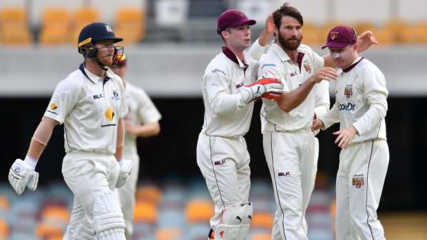 Over and out: Queensland bowler Michael Neser (2nd from right) celebrates the wicket of Victoria's Travis Dean on day three at the Gabba.