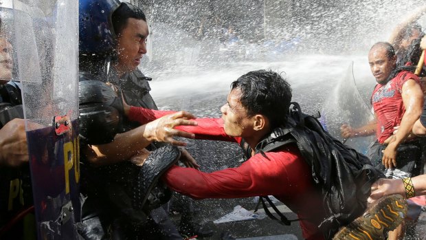 A protester pushes a policeman as they are dispersed while trying to get near the US Embassy in Manila, Philippines.