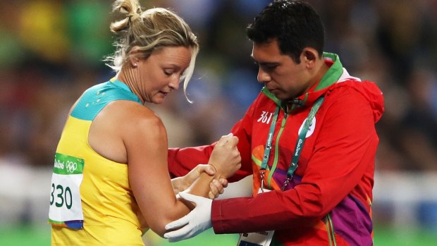 Kim Mickle of Australia is assisted by medical staff after popping her shoulder in the javelin. 