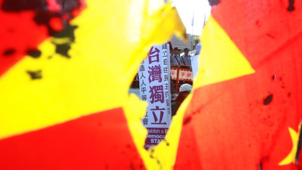 A protester holds a slogan reading ''Taiwan Independence'' is seen through a burned China national flag outside of the meeting place of the Taipei-Shanghai forum in Taipei, Taiwan.