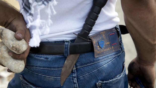 A Palestinian demonstrator carries rocks and has a knife tucked in his belt during clashes with Israeli troops near Ramallah.