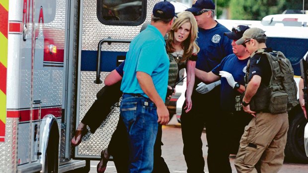 An injured woman is carried to an ambulance in Clovis, New Mexico, as authorities respond to reports of a shooting inside a public library. 