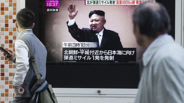 Pedestrians walk past a television screen broadcasting an image of North Korea leader Kim Jong-un.