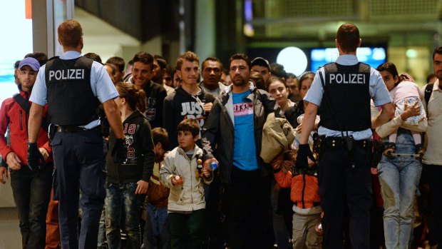 Refugees and migrants  are accompanied by police as they  arrive at the central train station in Munich, Germany.