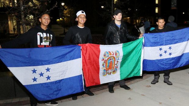 Josh Herandez, Francisco Hernandez, Devon LaLond and George Hernandez hold flags for Honduras and a traditional flag from Mexico to represent their heritage during an anti-Trump protest on the University of Wisconsin on Thursday.