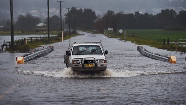 A local farmer crosses the flooded Illawarra Hwy after heavy falls across the region.