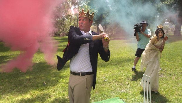 Warnie tries out his crown while hitting some cricket balls filled with coloured powder. 