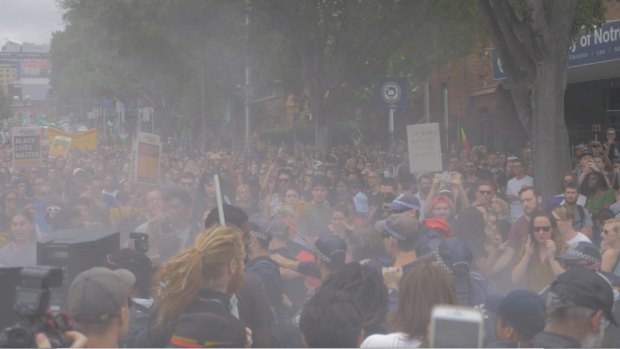 Haze from a fire extinguisher hangs over an Australia Day protest crowd on Broadway.