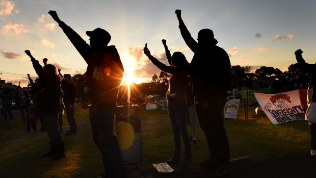 Aboriginal men and women raise their arms in support at the Block in Redfern before negotiations resolved the dispute.