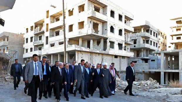 Syrian President Bashar Assad, centre, walks with officials througha  destroyed neighbourhood in Daraya after morning Eid al-Adha prayers.
