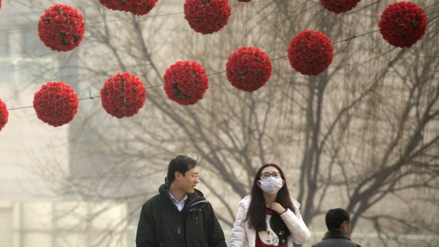 A woman wears a mask as she walks through Yuyuantan Park on a heavily polluted day in Beijing on Saturday.