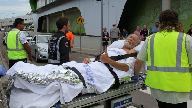A surfer who was bitten by a shark gives the thumbs up as he is wheeled into John Hunter Hospital.