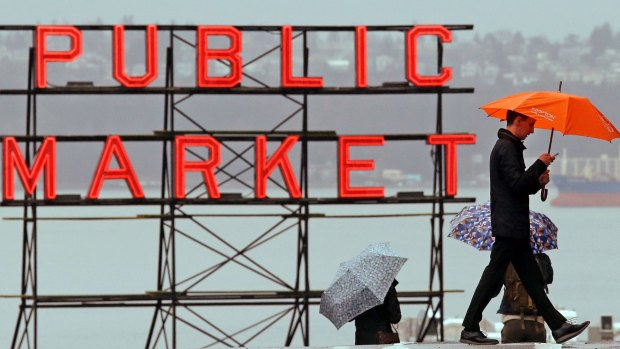 FILE - In this Jan. 18, 2017, file photo, pedestrians huddle under umbrellas as they walk past the Pike Place Market and in view of Elliot Bay, behind, in Seattle. The National Weather Service says the city has measured 44.67 inches of rain in the city between October 2016 and so far in April. That makes it the wettest such period since records began in 1895. Meteorologist Mike McFarland in the agency's Seattle office says it's the second year in the row that the city had topped the rainfall record for that 7-month period. (AP Photo/Elaine Thompson, File)