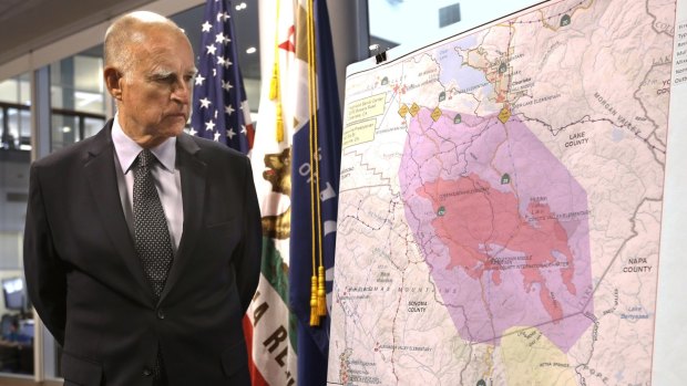 Droughts and fires ... California Governor Jerry Brown examines a map showing the location of fires in California. 