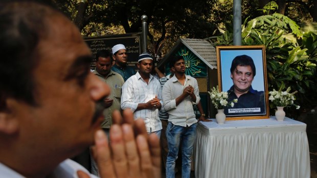Friends and relatives offer prayers near a portrait of one of the victims during his funeral at a graveyard in Mumbai.