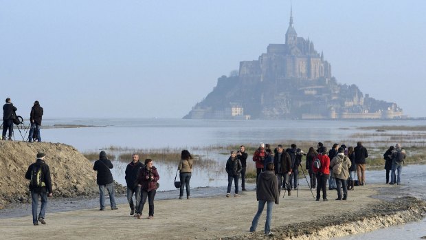 People gather ahead of a high tide submerging a narrow causeway leading to the Mont Saint-Michel, on France's northern coast.