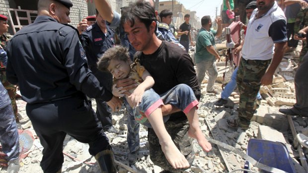 A man carries an injured child away from the scener of the New Baghdad bombing.