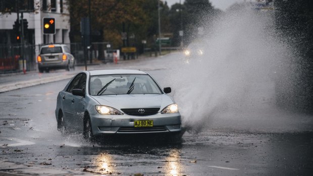 A car passes through water flooded road on London Circuit in Canberra.