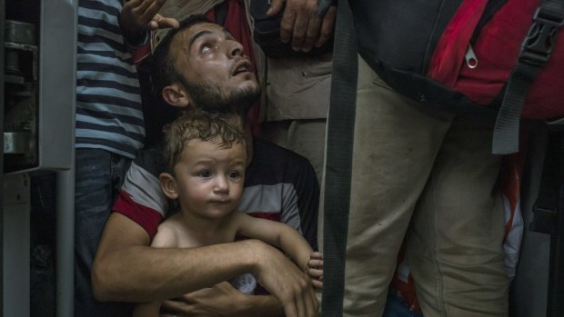 A refugee holds his son as they wait for a train to leave Budapest, Hungary, on September 3.