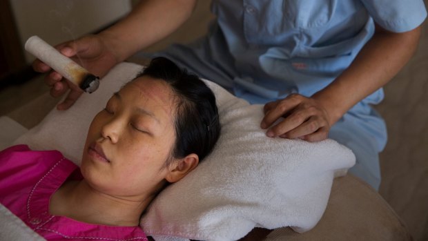 Li Rui undergoes a moxibustion treatment -- with smoking sticks of mugwort -- to help prevent disease.