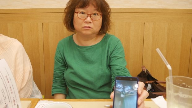 Yoshiko Furukawa uses her mobile phone to show photos of the damage the 2011 Tohoku earthquake inflicted on her house in Fukushima.
