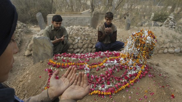 Condolences: Friends of a student killed in the attack offer prayers at his grave in Peshawar.