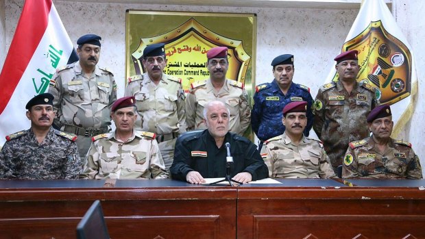 Iraqi Prime Minister Haider al-Abadi, in black and surrounded by top military and police officers, announces the start of the operation to liberate Mosul.