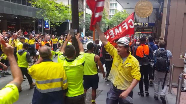 Construction workers boo and wave flags as John Howard is escorted down the footpath.