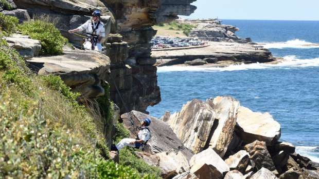 Police abseil down the cliff to the woman's body.
