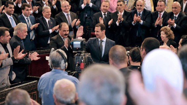 Syrian President Bashar Assad waves as he arrives to address the newly-elected parliament in Damascus.