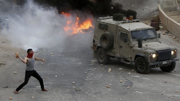 A Palestinian youth throws rocks at an Israeli military vehicle in the West Bank city of Nablus.