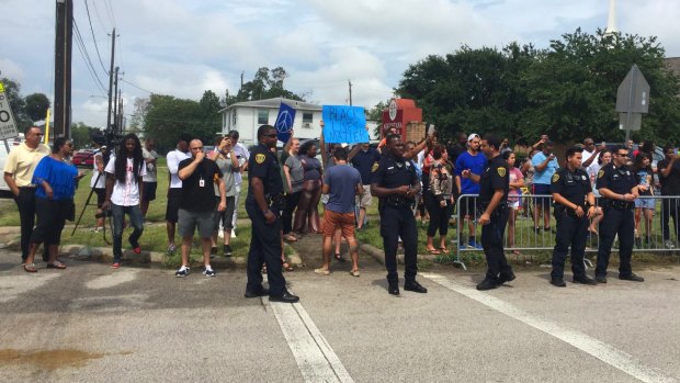 Houston police officers stand by counter-demonstrators assembling across the street from people with White Lives Matter signs outside the NAACP office in Houston