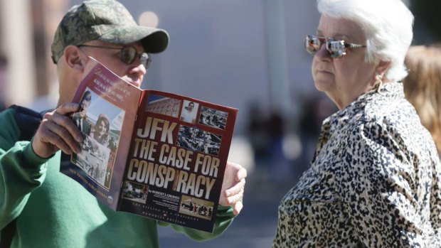 A vender shows a woman a magazine during her visit to Dealey Plaza in Dallas, Texas. 