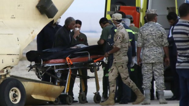 Egyptian emergency workers unload bodies of victims from the crash of a Russian aircraft carrying 217 passengers and 7 crew.