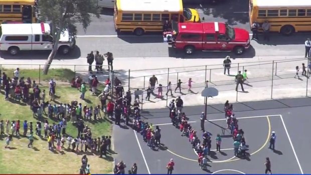 Children are evacuated to school buses to be reunited with their parents after the shooting.