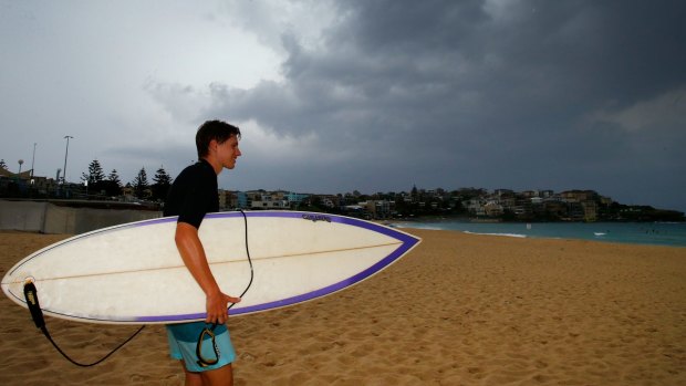 A man walks towards the water at Bondi beach as storm clouds start to dissipate.