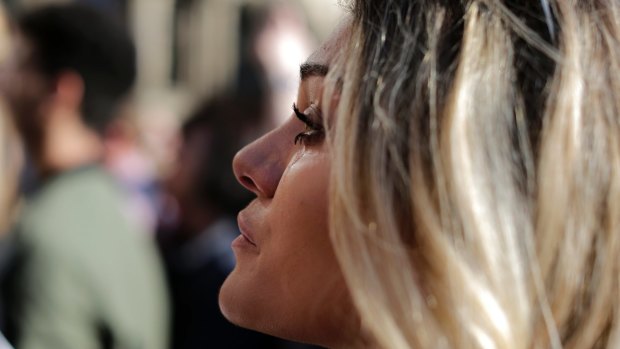A woman cries as she attends a vigil in Albert Square, Manchester, England.