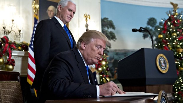 US President Donald Trump signs the proclamation next to US Vice-President Mike Pence.