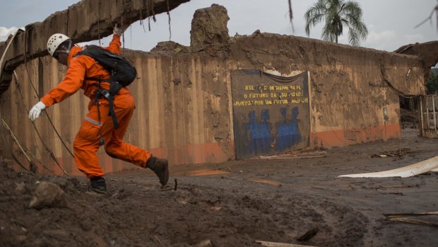 A rescue worker walks near the destroyed school at the site where the town of Bento Rodrigues stood after a dam burst on Thursday, Brazil.