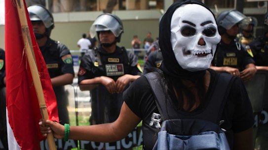A protester in mask holds a Peruvian national flag during a rally against the Trans Pacific Partnership in Lima, Peru in November 2016.