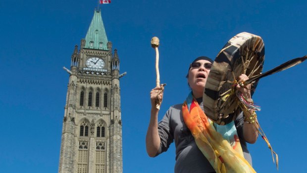 Marcia Brown Martel sings outside Canada's parliament buildings following the news of the settlement in Ottawa.